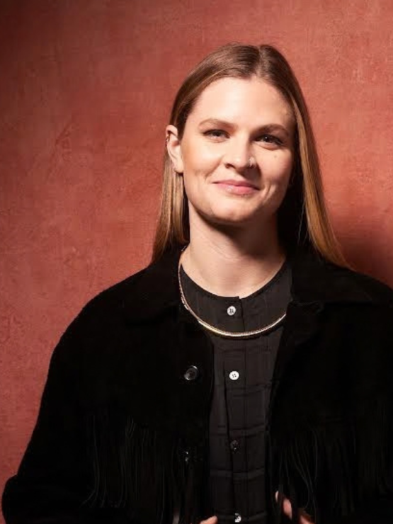 a white woman with straight blond hair poses in a black jacket