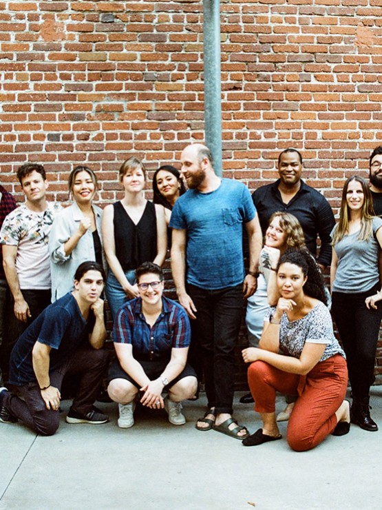 fourteen people stand in front of a brick wall