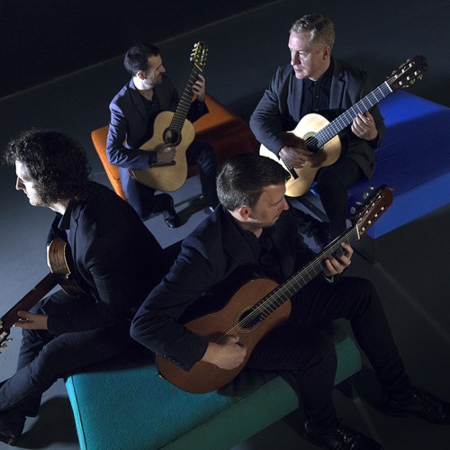 from above, with blue light casting shadows, four white men sit on the sides of a square box, turned in various directions