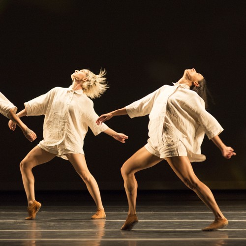 dancers wearing ivory linen rompers stride forward as they lean back and lift their heads up in unison