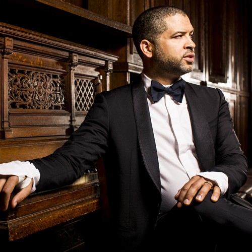 Jason Moran, a black man in a tuxedo sitting in front of a piano.