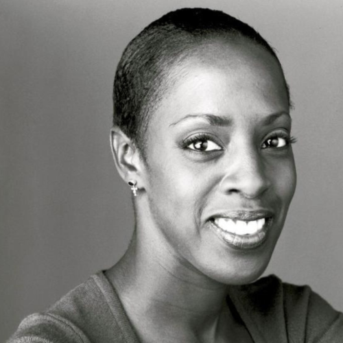 a black and white, portrait of a smiling black woman, turned most of the way toward the camera