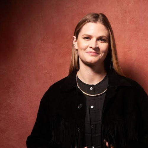 a white woman with straight blond hair poses in a black jacket