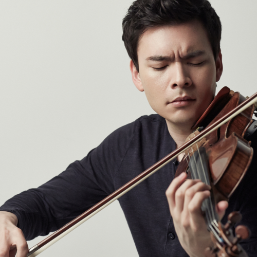 a young man with korean and german heritage plays the violin. his brows is furrowed and his eyes are closed