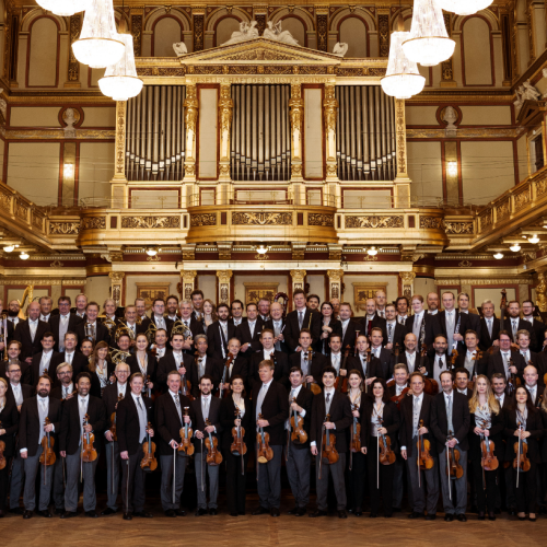 a symphony orchestra in concert dress inside a golden neoclassical concert hall