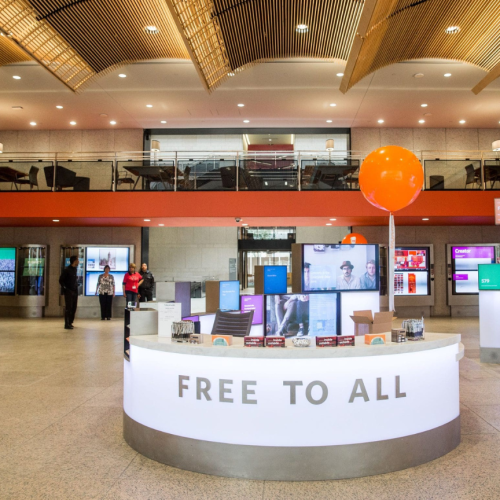 a library information desk in a modern-style lobby. large letters on desk read "free to all"