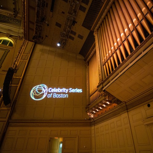 celebrity series logo projected on a side wall of symphony hall's stage. The pipes of the organ make up most of the picture.