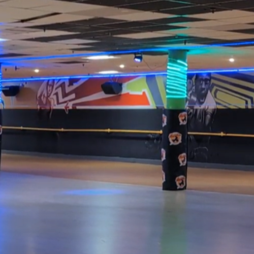 the interior of a roller skating rink, with carpeted columns and colorful grafitti inspired murals