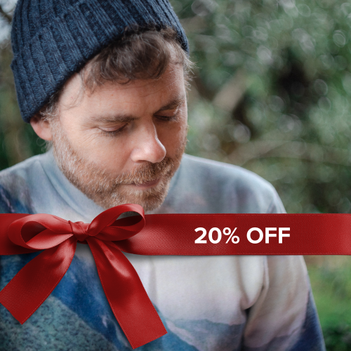 a white man with a short beard wears a beanie outdoors among conifer trees. ribbon overlay reads 20% off
