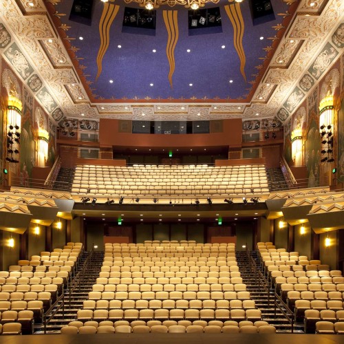 A view from the stage into the two level auditorium, the walls are adorned with art deco paintings and designs