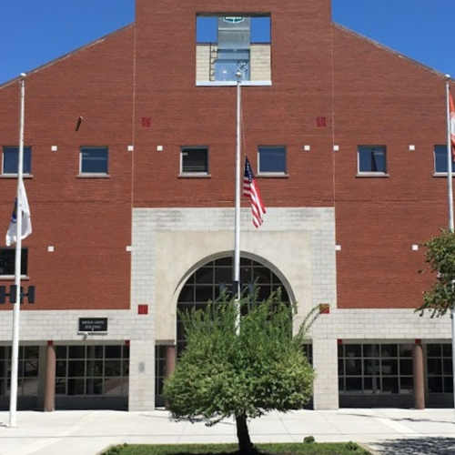 A large brick building with tress and flag poles out front