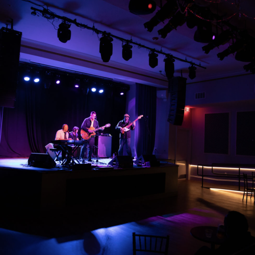 A small jazz band performs in a dark bar venue