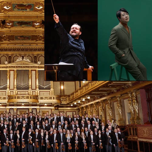 A very large orchestra dressed in formal concert attire stands together holding their instruments in a large ornate room. 