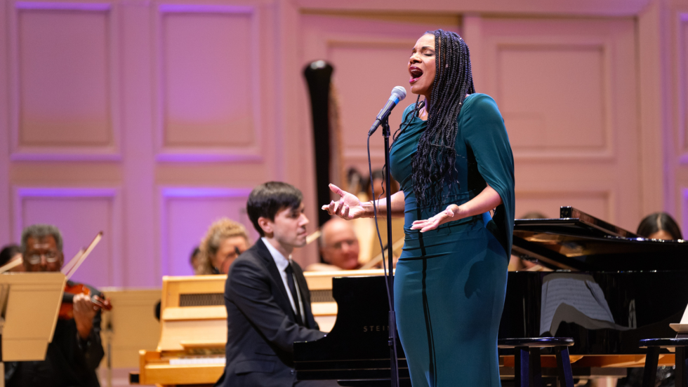 audra mcdonald sings an emotional song in front of an orchestra, her face expressive, her gesture pleading.