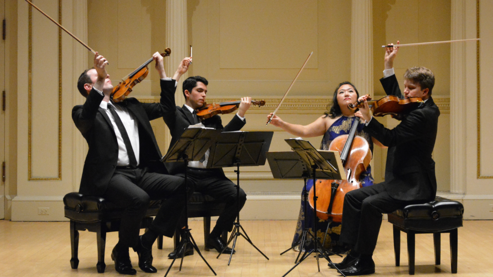 a string quartet raises their bows with a flourish at Carnegie Hall