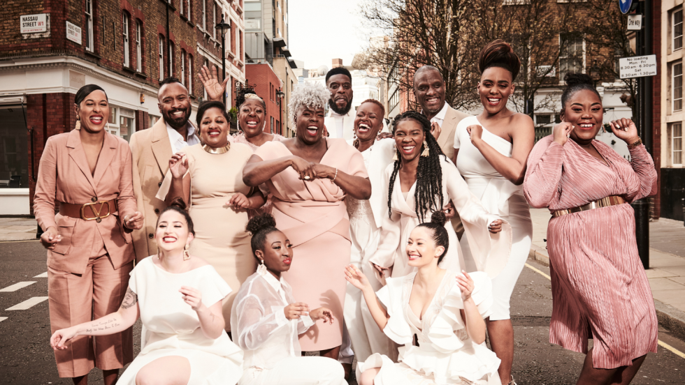 wearing ivory, beige, and rose, the members of the kingdom choir on a street in London