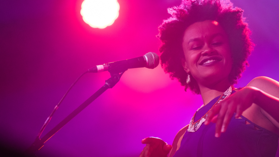 in pink light, meklit looks down and to her left toward the camera