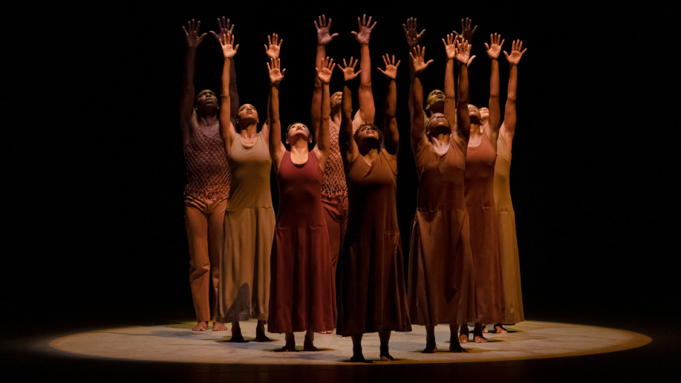 ailey dancers performing, arms raised straight up and hands open