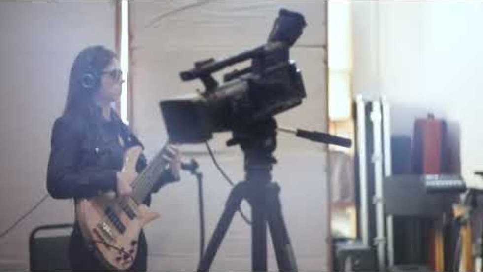 a nine-piece band, led by Ciara Moser, a bassist who is blind, performs in a recording studio surrounded by audio equipment and sound dampening panels