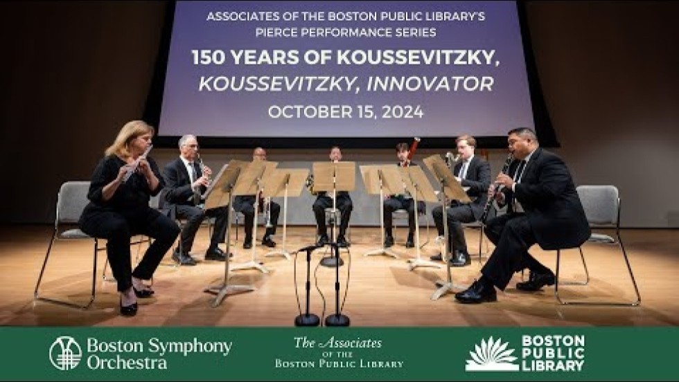 seven musicians in a semicircle perform on a draped stage at the Boston Public Library
