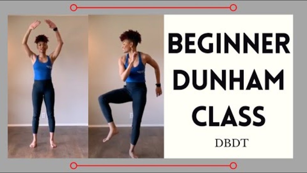 a black woman, with reddish brown hair in a curly high fade and a blue athletic tank and black leggings, leads a class in a studio. African drums and a potted plant are behind her.