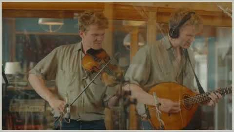 a folk trio performs and records in a wood-paneled studio