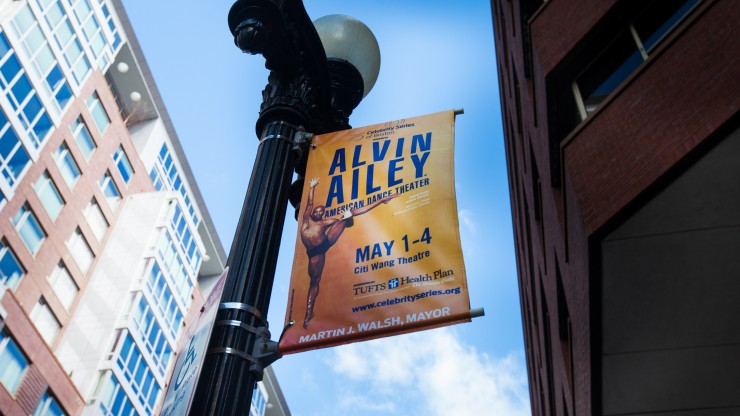 A banner attached to a lamppost advertising Celebrity Series’ engagement of Alvin Ailey. A dark-complexioned male dancer wearing a black dance belt is posed with arms and legs extended in a ballet position. 