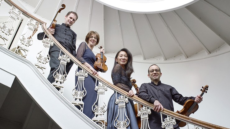 on a curving white staircase a string quartet holds their instruments