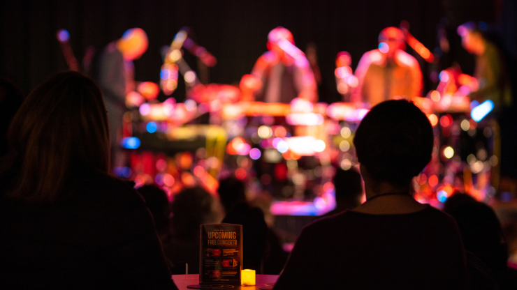 silhouetted audience members watch a percussion ensemble in a nightclub