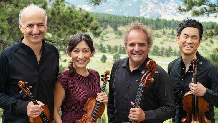 a string quartet holds their instruments in a mountain meadow
