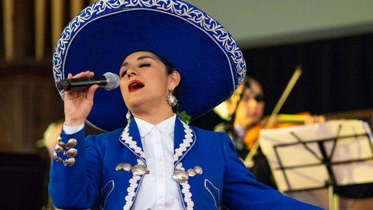 a mariachi singer in a bright blue suit performs for her audience