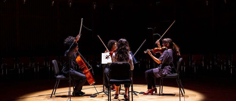 a string quartet in a circle of golden light finishes a performance with a flourish