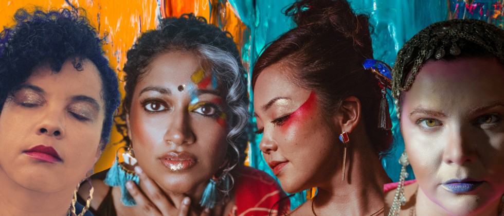 An international group of women with paint on their faces and dark hair are photo shopped elegantly onto a background of orange, teal, and rainbow paint. 