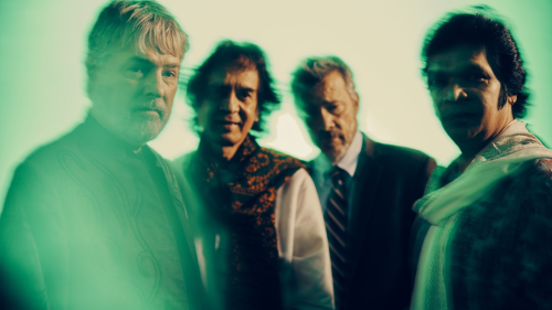 An abstracted photograph of four men looking at the camera. Their images are distorted with a green blur effect