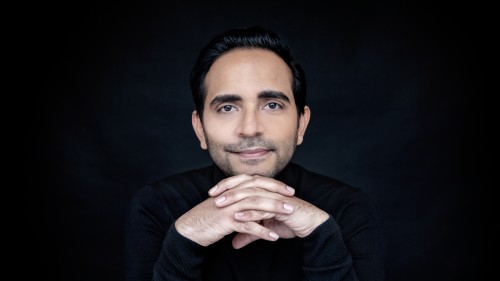 a latino man rests his chin on his tented hads