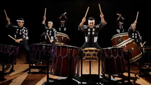 A large group of Japanese musicians perform on their taiko drums. 