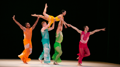 Paul Taylor dancers in colorful outfits joyfully lift up and carry another dancer