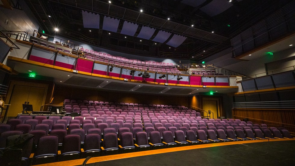 A view from the stage into a large school auditorium with purple theater seats