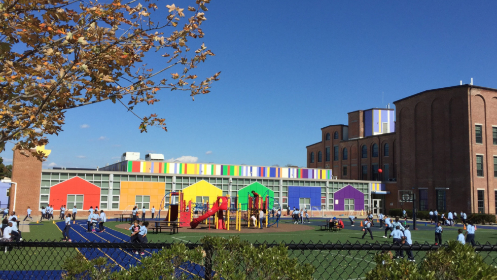 a colorful painted wall overlooks a playing field near a brick building