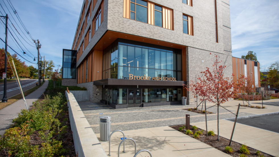 the entrance to a midrise contemporary high school building with orange trim around the windows