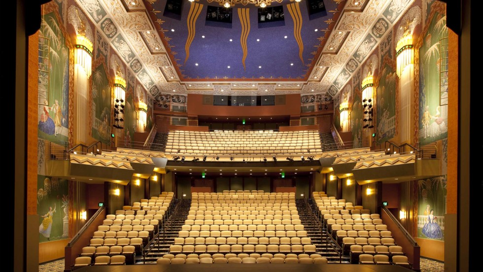 A view from the stage into the two level auditorium, the walls are adorned with art deco paintings and designs