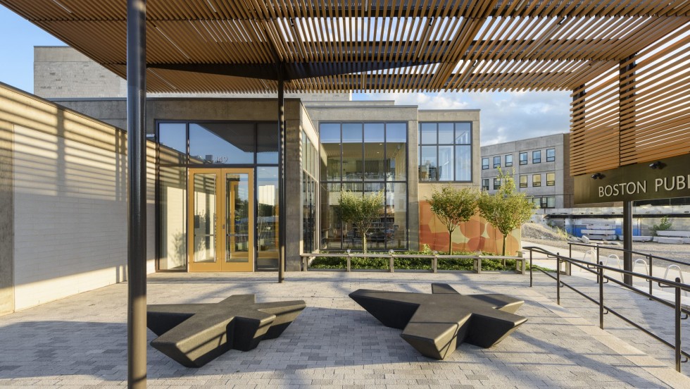 an outdoor patio with a slatted wooden sunshade on two sides that casts stripey shadows on a sunny day